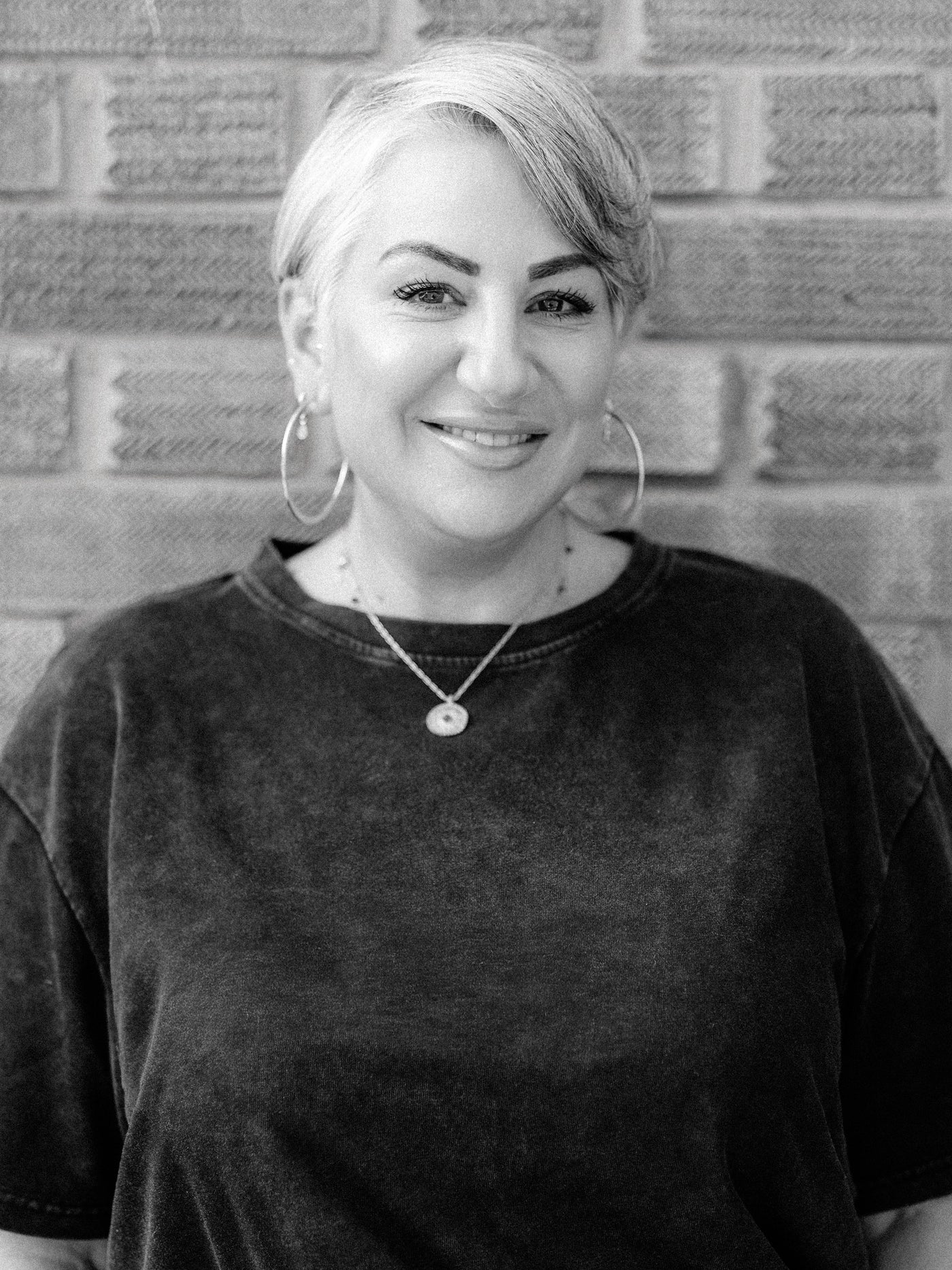 Black and white portrait of Method Hair Salon front of house team member Katie ,a smiling woman with short hair.