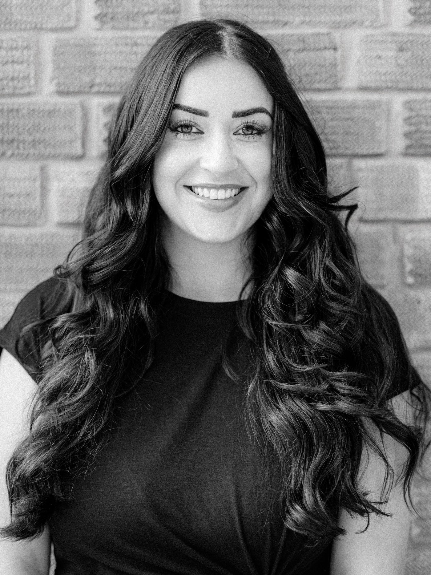 A black and white portrait of Method Salon  senior stylist Megan, a smiling woman with long hair.